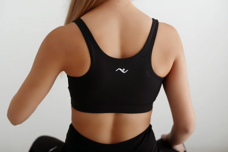 Czarny damski top ułożony na plecach modelki