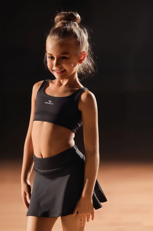 Modelka na sali tanecznej prezentuje czarny top dla dziewczynki ActivGlow