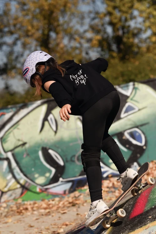 Bluza dziewczęca FLOW z odkrytymi ramionami czarna - modelka na deskorolce