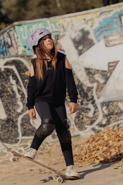 Czarna bluza dla dziewczynki z wycięciami na ramionach i kapturem - modelka na skateparku