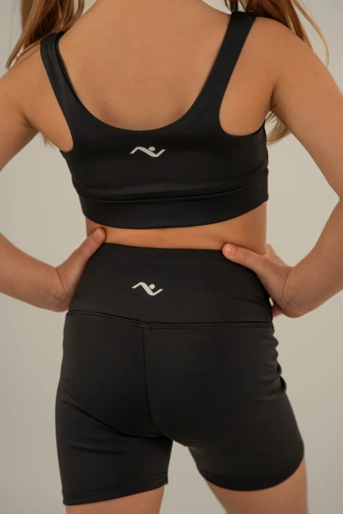 Czarne krótkie getry dziewczęce widoczne z tyłu z logo i sygnet na pasie