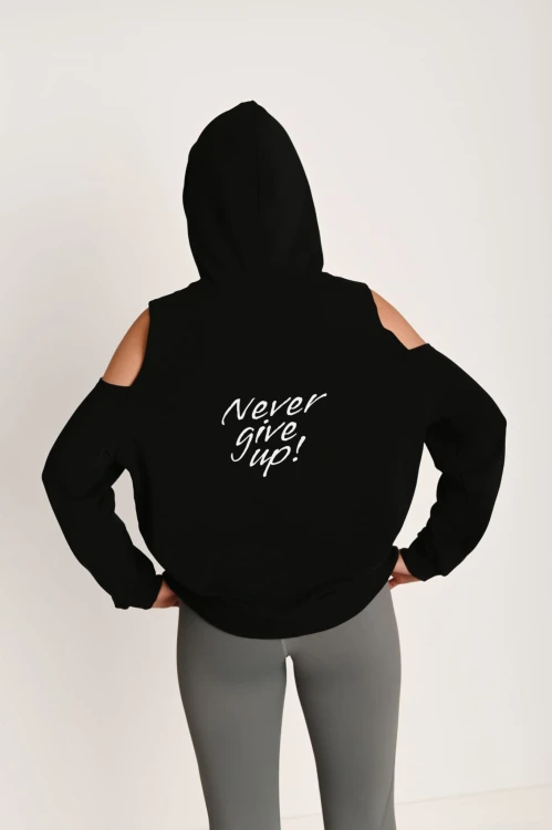 Modelka prezentuje bluzę z wyciętymi ramionami i kapturem z napisem na plecach Never Give Up