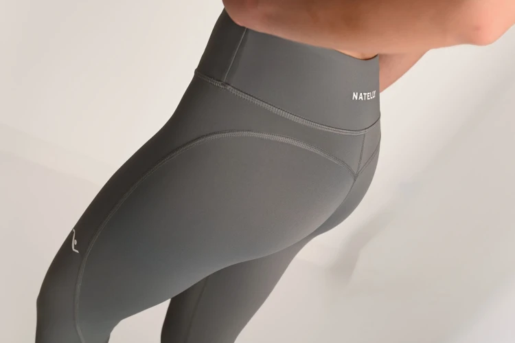 Przeszycia widoczne na tylnej części szarych legginsów damskich Natelly