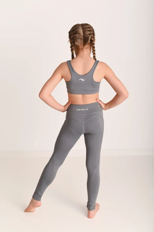 Legginsy dziewczęce z przeszyciami ActiveGlow szare - modelka stoi tyłem