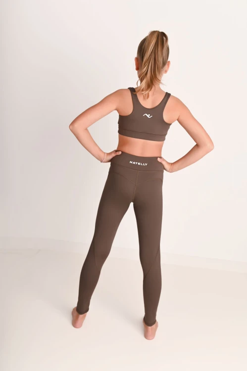 Komfortowe legginsy dziewczęce z przeszyciami ActiveGlow brązowe - modelka stoi tyłem